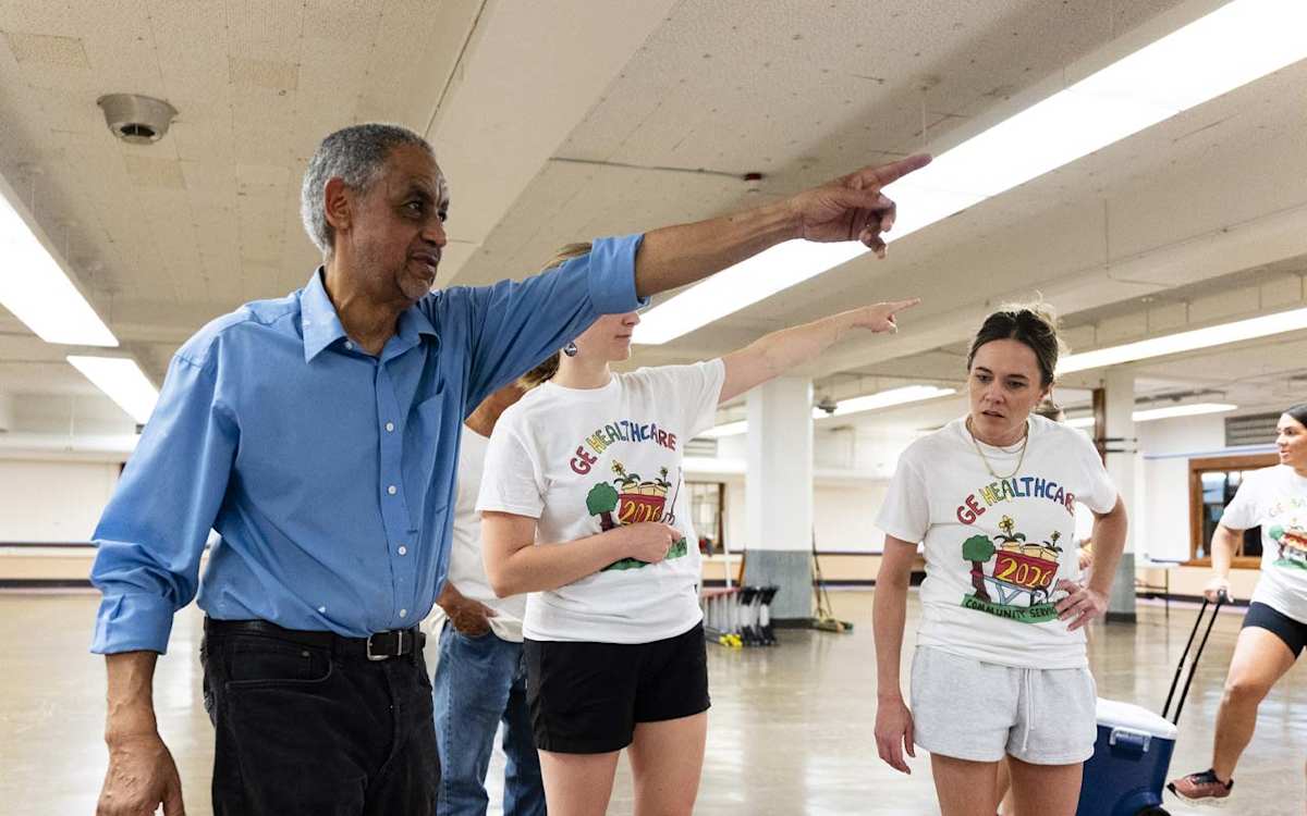 Milwaukee muralist and MPS alumnus Reynaldo Hernandez instructs volunteers who will help him paint a mural at ALBA's cafeteria.