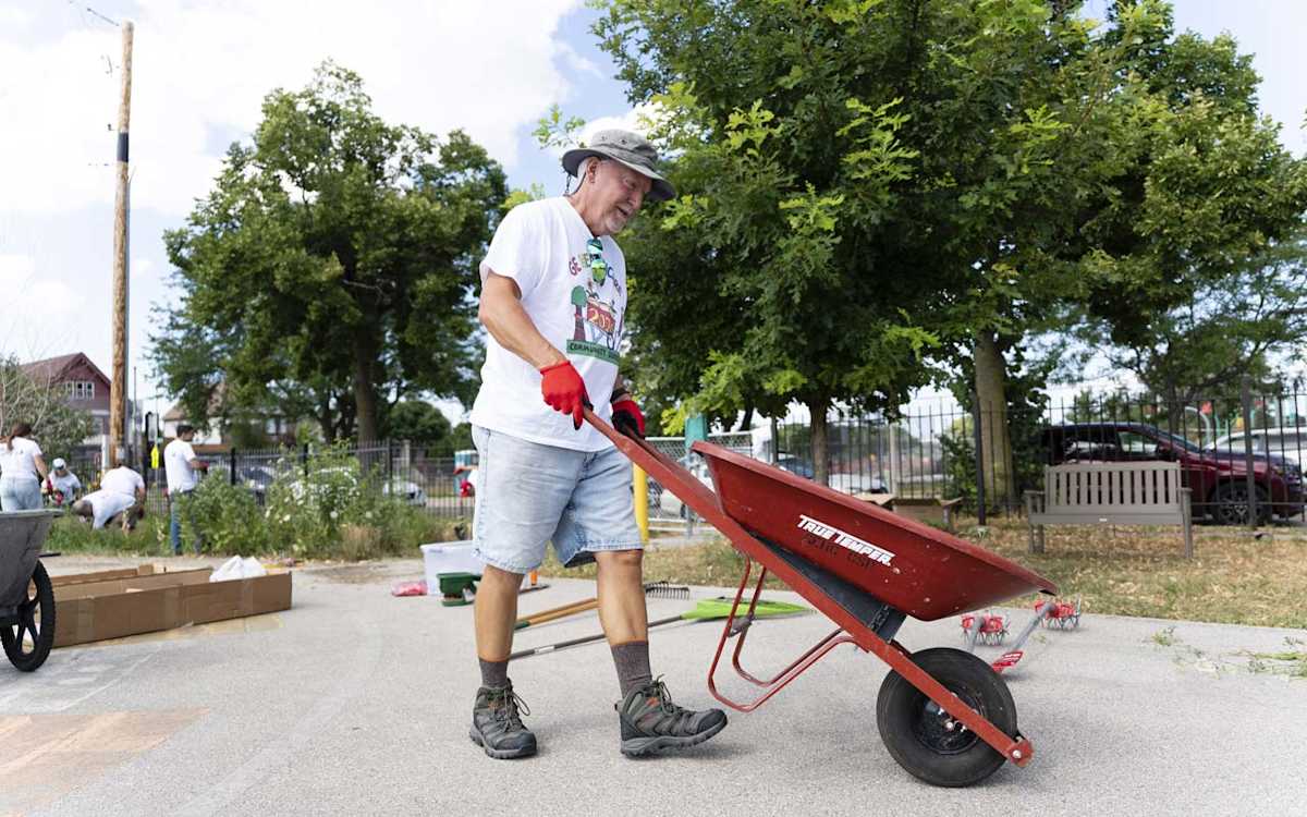 A GE HealthCare volunteer pushes a wheelbarrow while landscaping at ALBA.