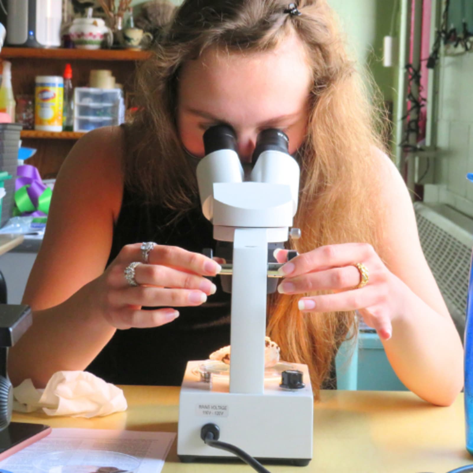 Aluna usando um microscópio em aula de ciências