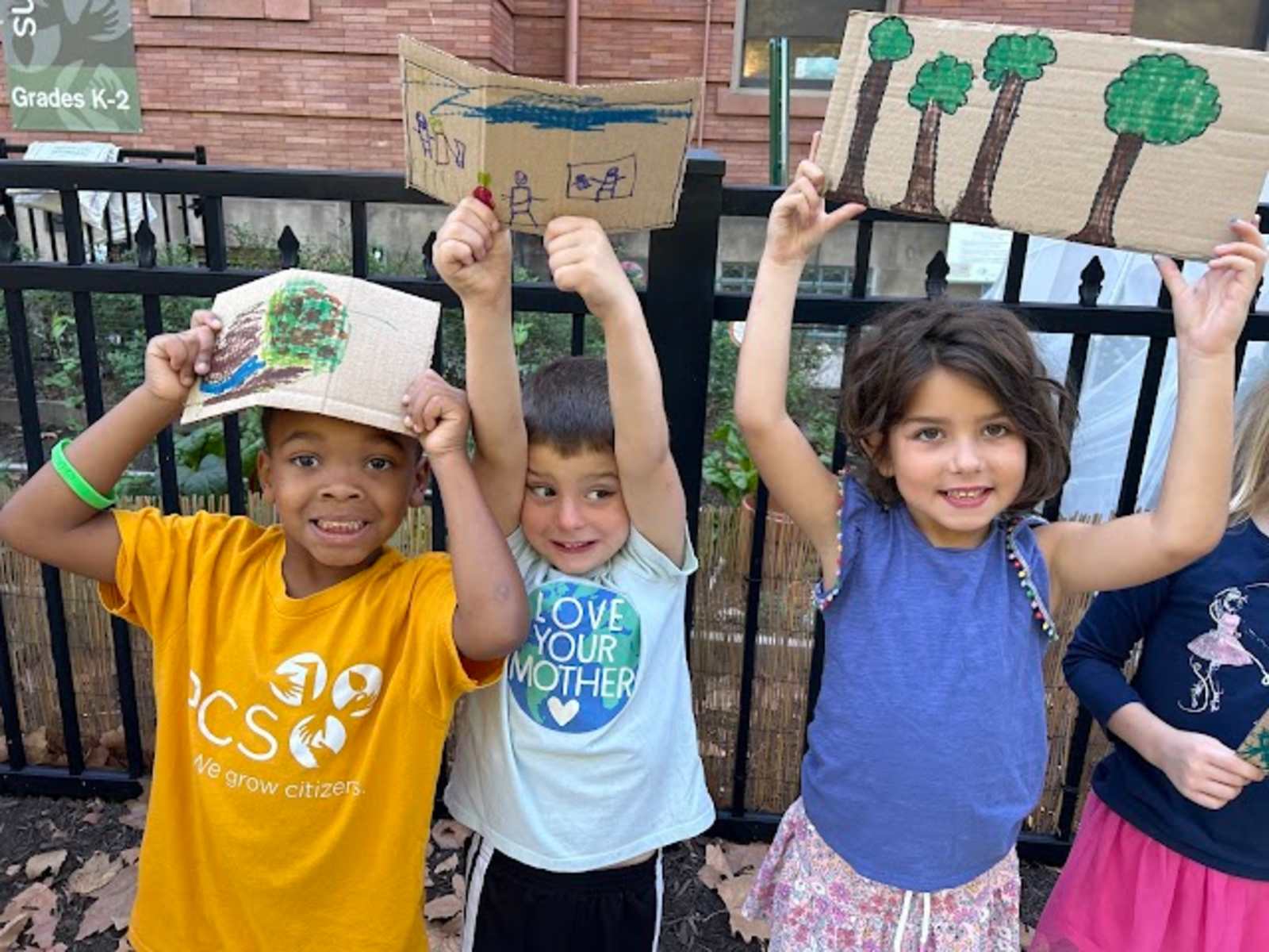 Primary students holding up nature drawings