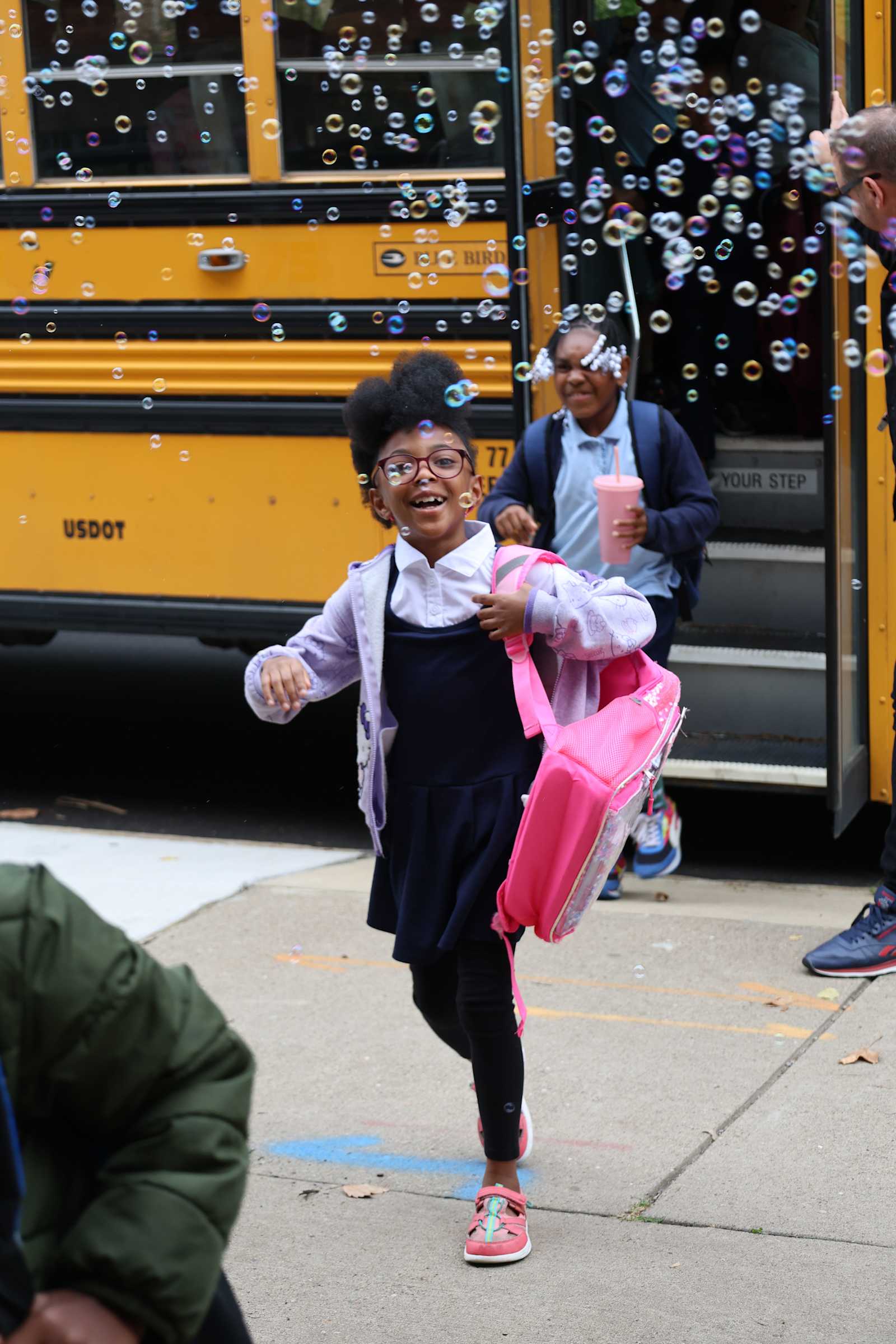 A Primary student arriving at school through a cloud of bubbles