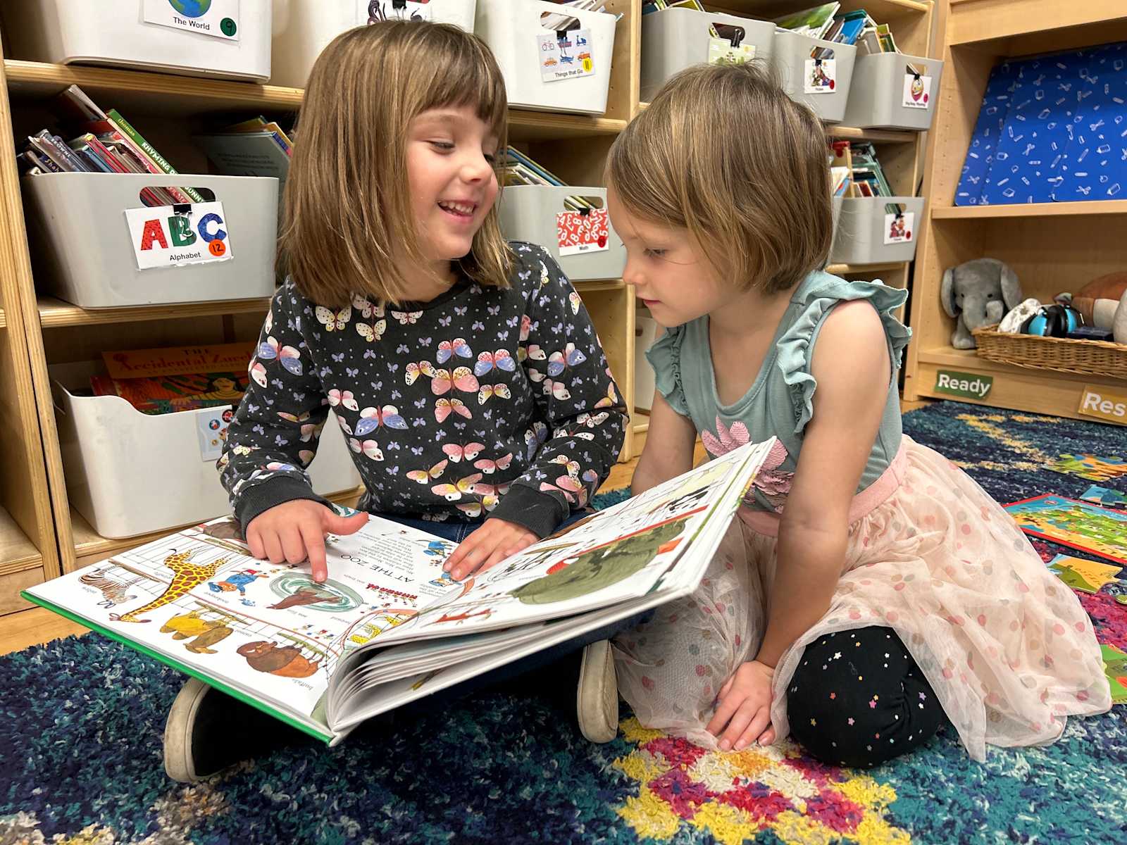 Two Primary students sharing a picture book on the classroom rug