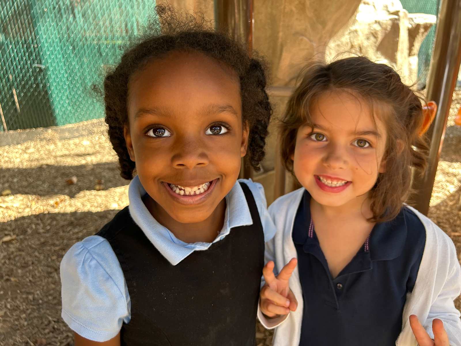 Two Primary students smiling outside on the playground