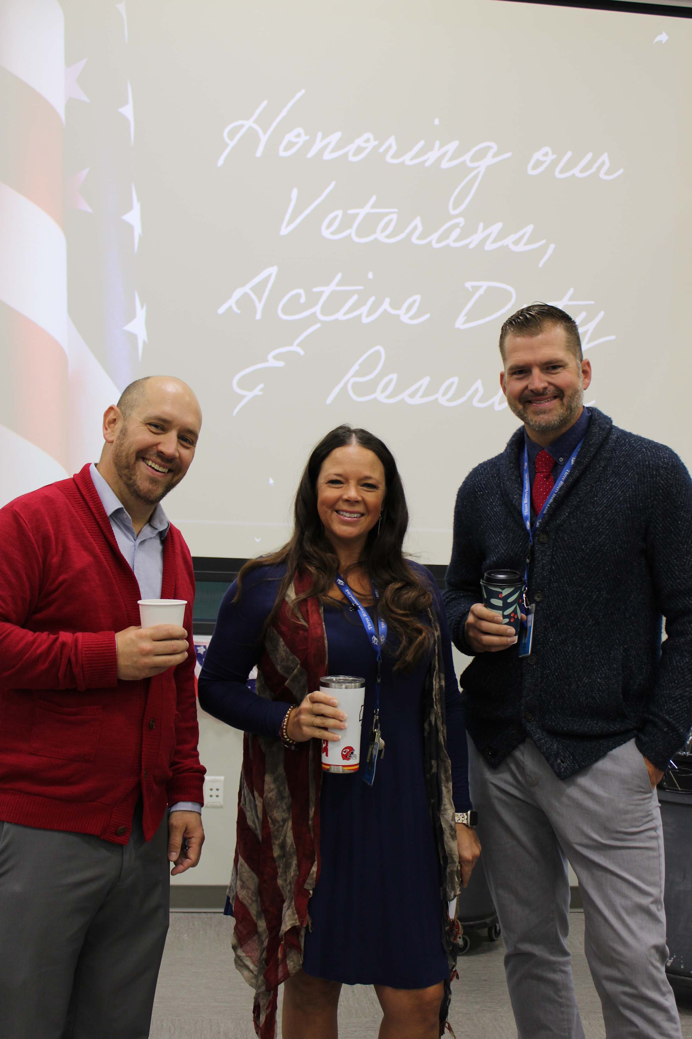 The image shows three people standing in front of a whiteboard with the text %22Honoring our Veterinary Active Duty and Reserves%22 written on it.