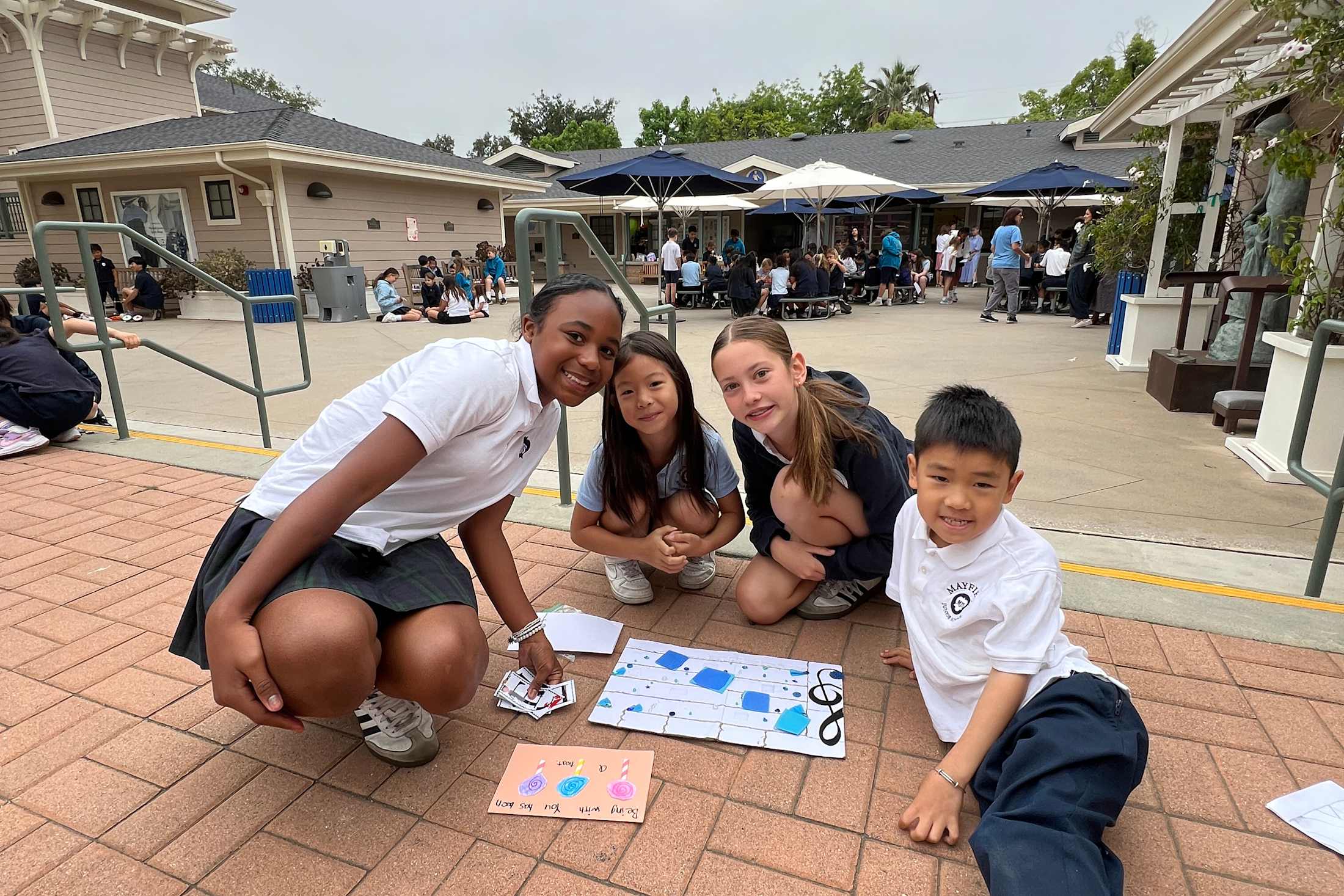 6th graders with kindergarteners working on a project outside