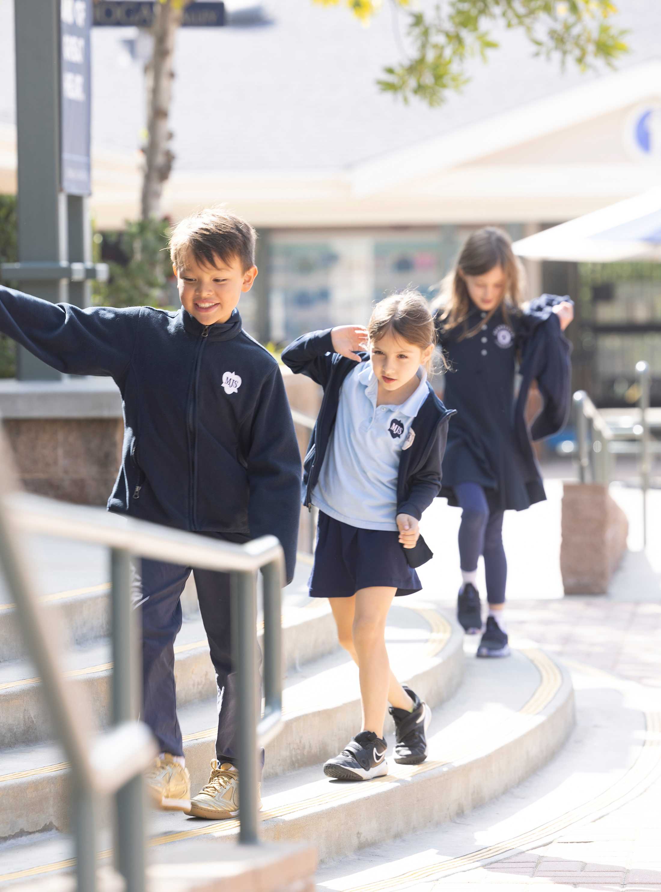 Three students walking across campus in single file and smiling 