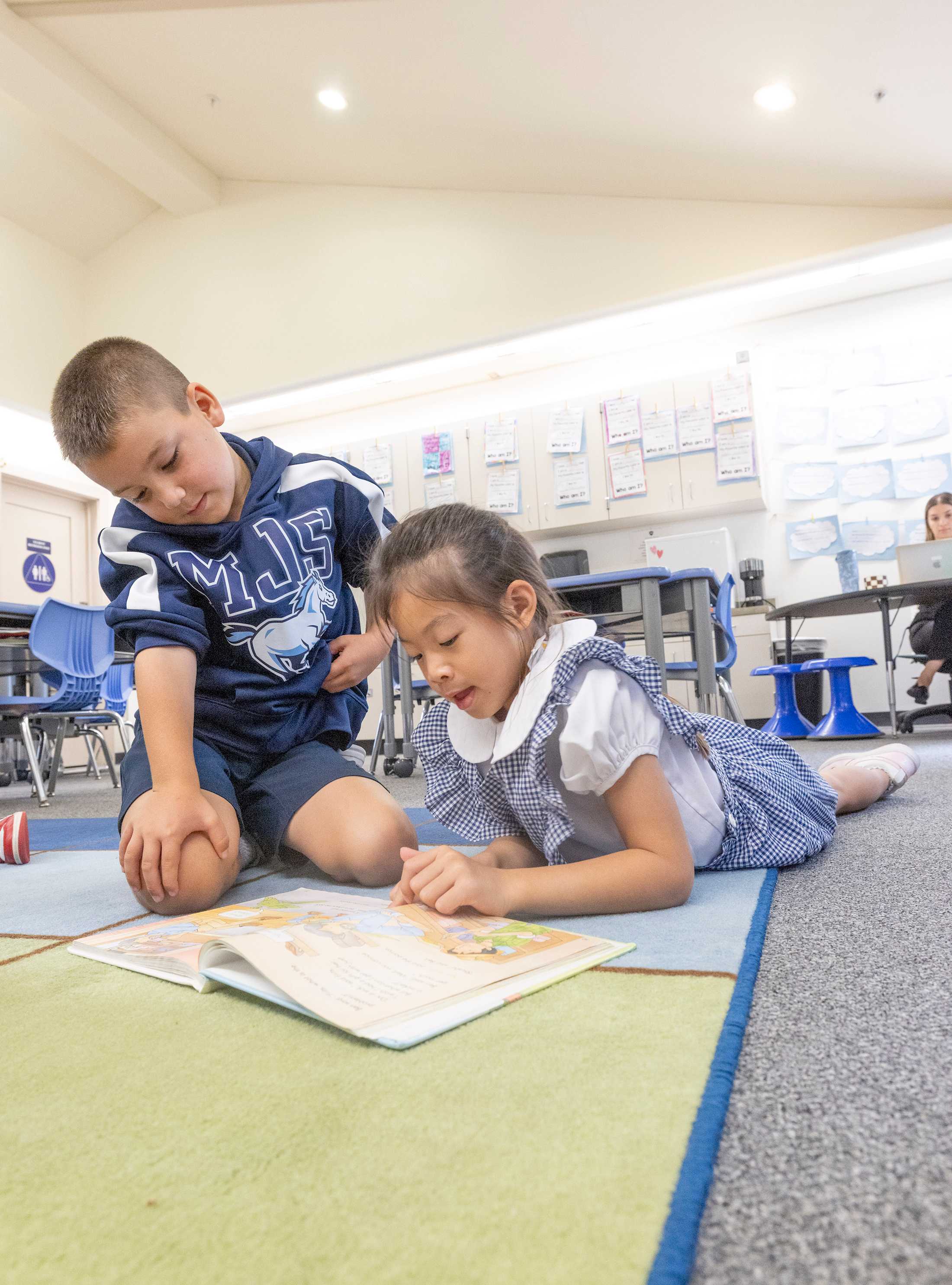 Boy and girl looking at a book together while sitting on the floor