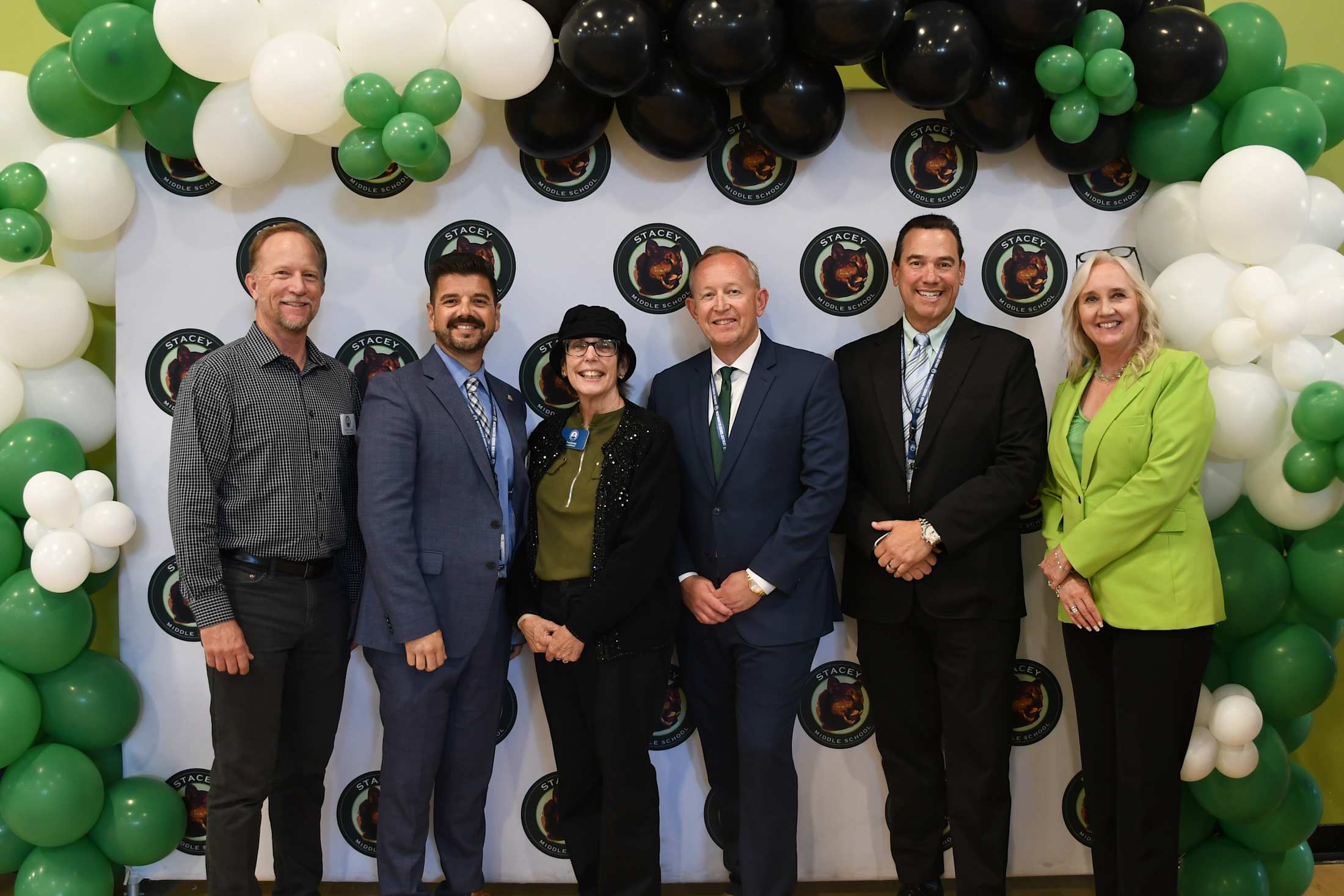 Admin and board members standing in front of a banner that showcases the Stacey logo.