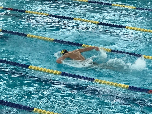 The image depicts a swimmer in a swimming pool, with clear blue water and lane markers visible in the background.
