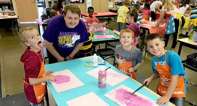 Hanford High senior Remington Steelman works with White Bluffs Elementary students on illustrations on "Hamilton Wants..."