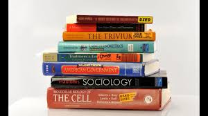 A stack of various textbooks and reference materials on subjects such as sociology, biology, and general knowledge.