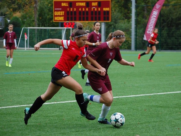 Varsity Girls Soccer in action with FIS scoreboard in background