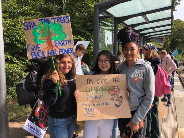 Upper School girls on U-Bahn platform holding environmental justice signs