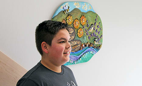 Vincent, a fifth-grader, stands in front of one of the panels made by artist Melissa Cole for "Tapteal Journey"