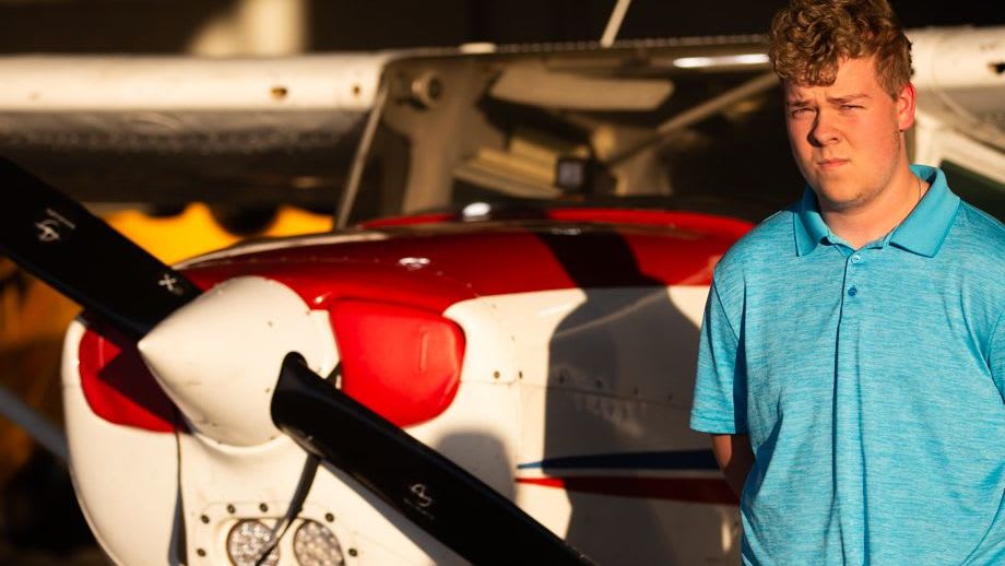 A student from the Bluegrass Experience Program stands next to an airplane.