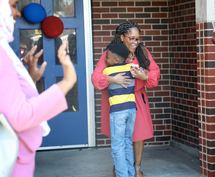 Dr. Collier gives a hug to a child entering the global academy