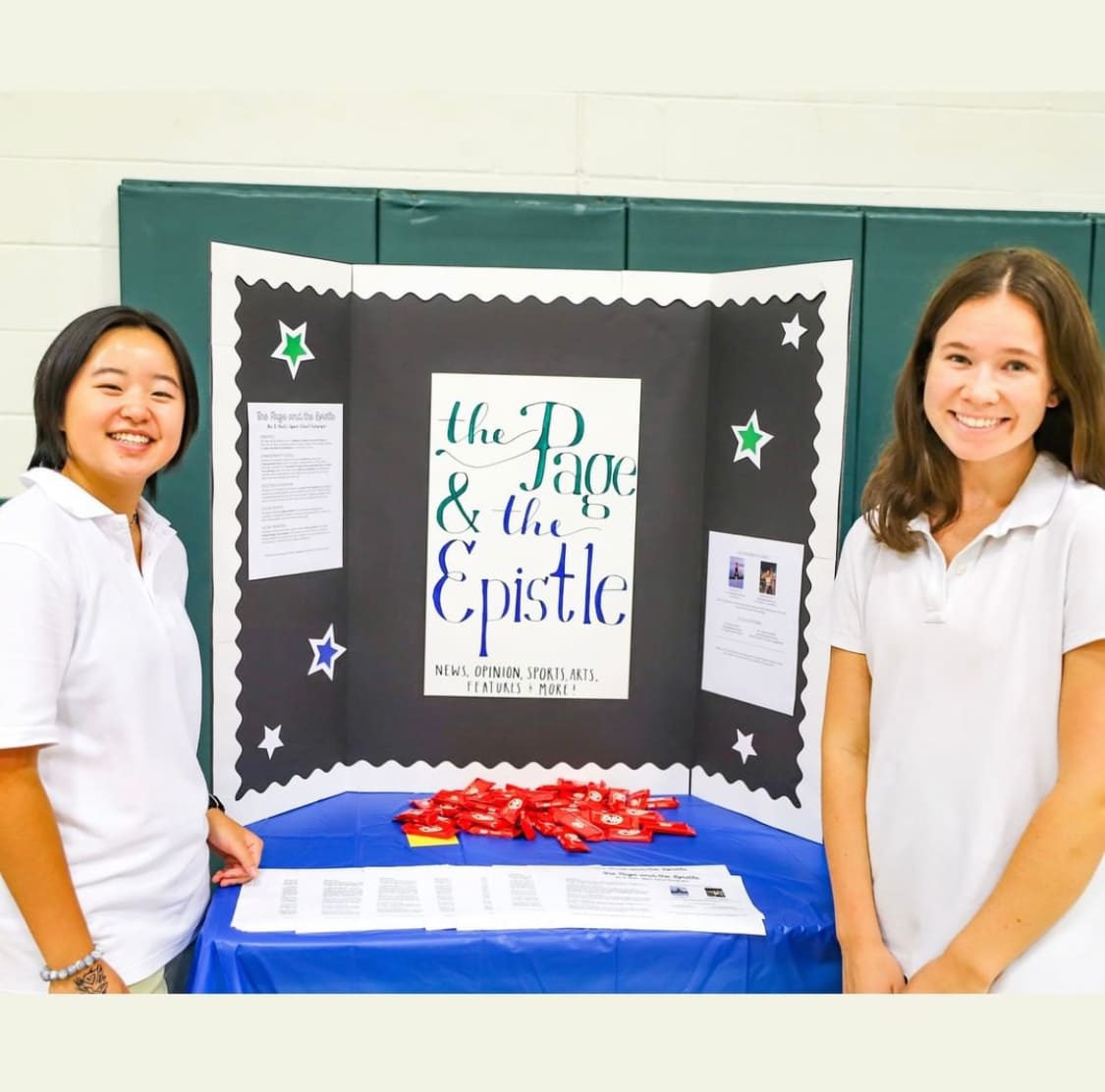 Two girls stand by newspaper club poster