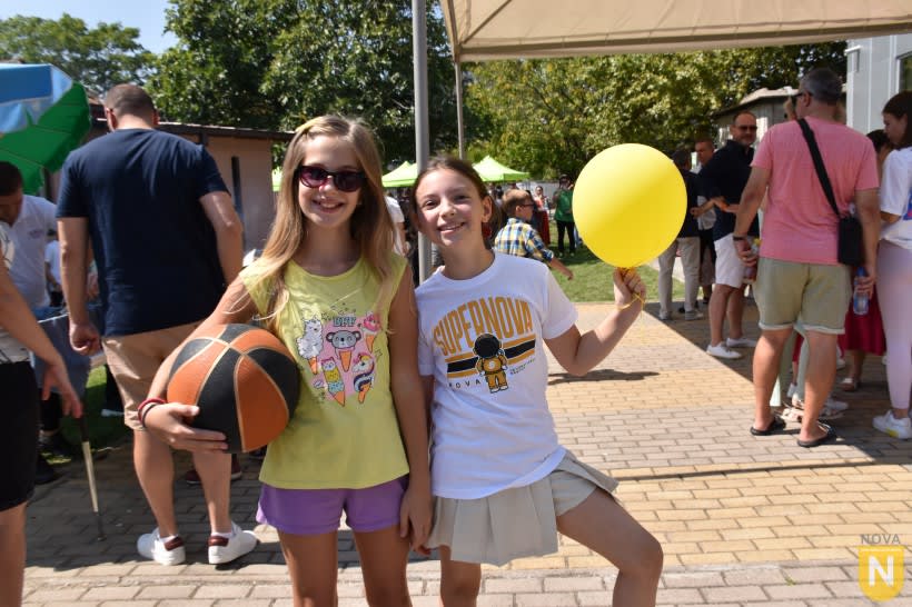 Two girls posing with a basketball and a yellow balloon at the PTA BBQ