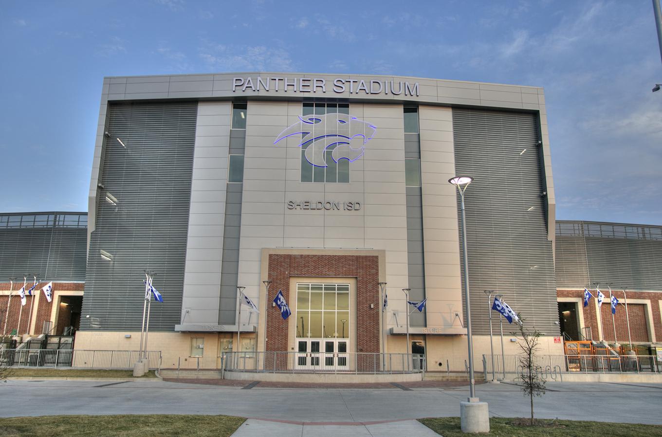 A large, modern Panther Stadium building with a panther logo stands under a clear blue sky.