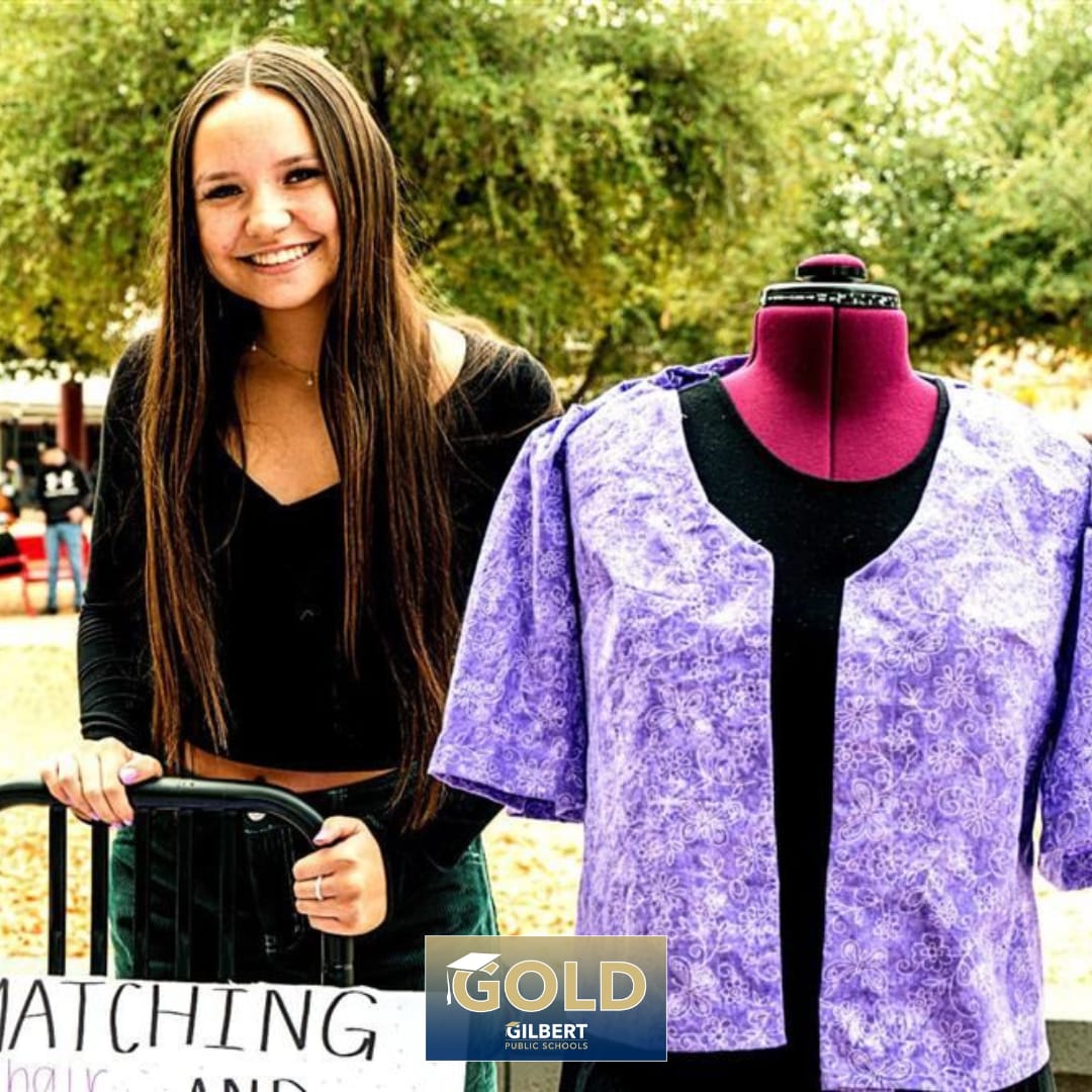 Photo of Desert Ridge High student poses next to a hand-made outfit from the Fashion and Design CTE program.