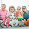 Elementary students sitting on a gym floor holding gym balls