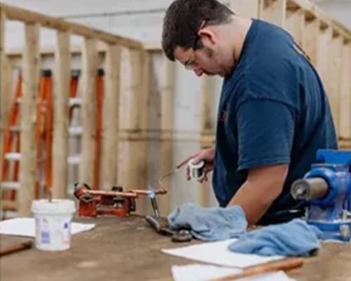 Plumbing apprentice working on pipes