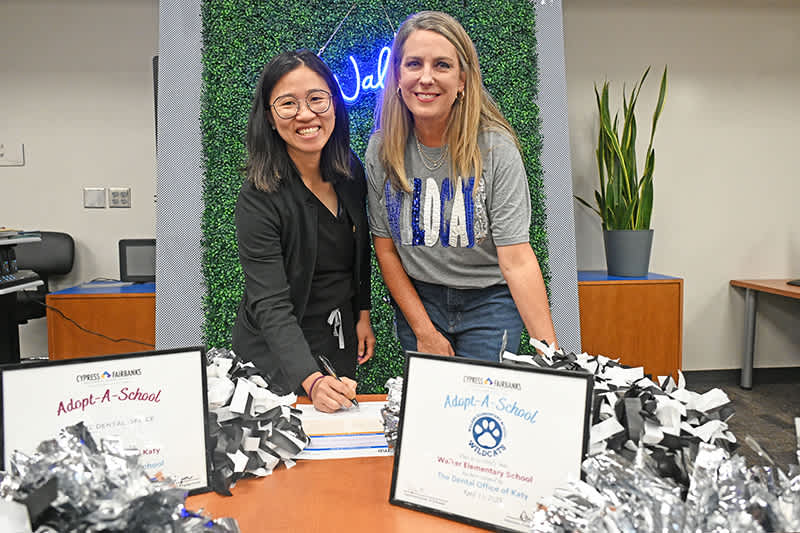 Dr. Nhu Dao, dentist with The Dental Office of Katy, left, signs an Adopt-a-School partnership agree…