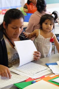 Mother and toddler daughter looking at math papers