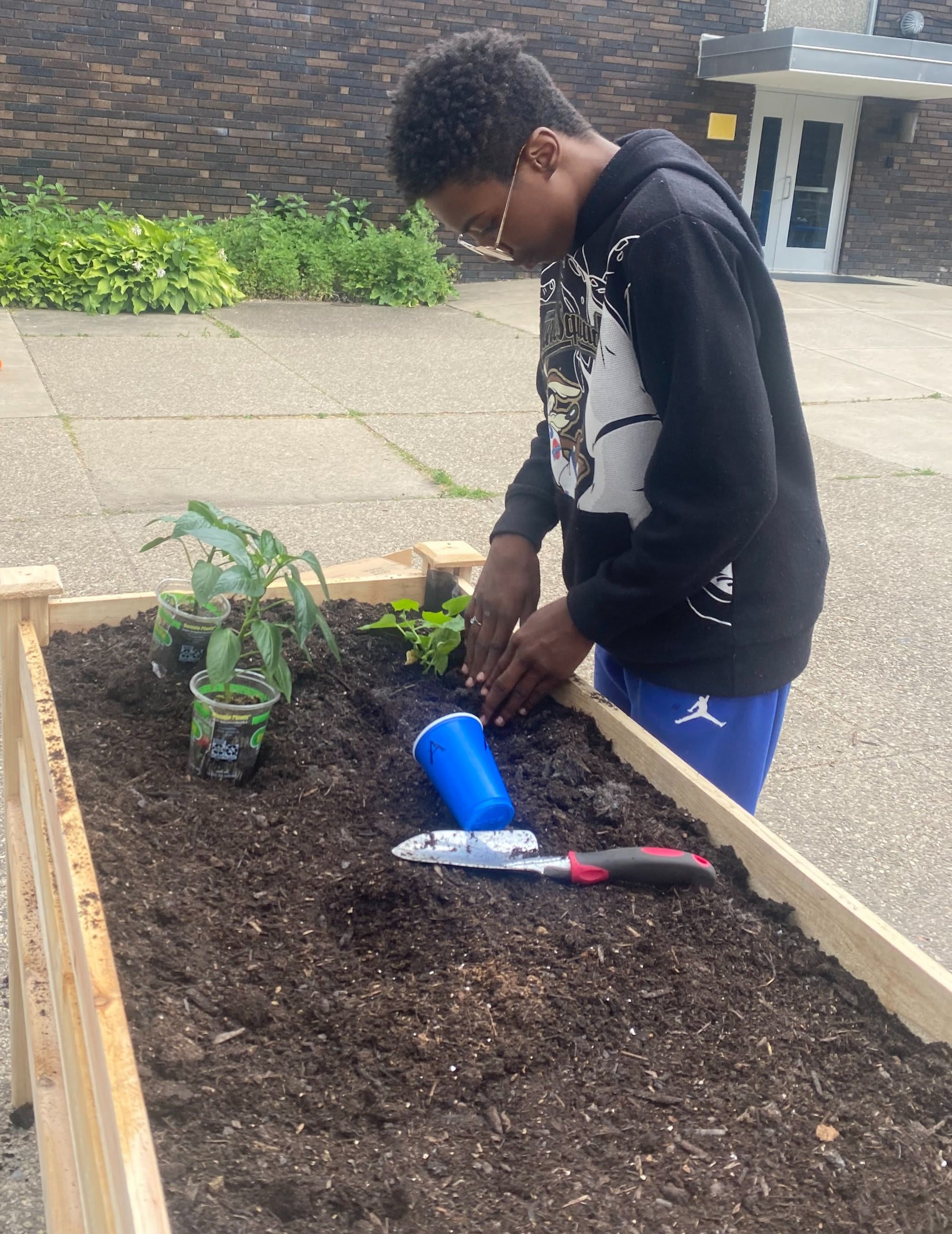 An Environmental Charter High School student tending a raised garden bed outside the school