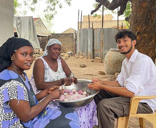 Lakeside student Taimur sits with two Senegalese women, washing vegetables