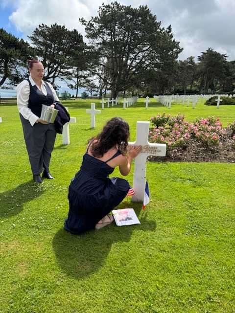 Student at cross marking grave of soldier she researched.