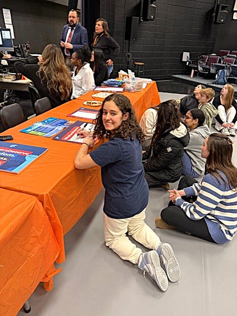 Girl kneeling in front of table with orange cover