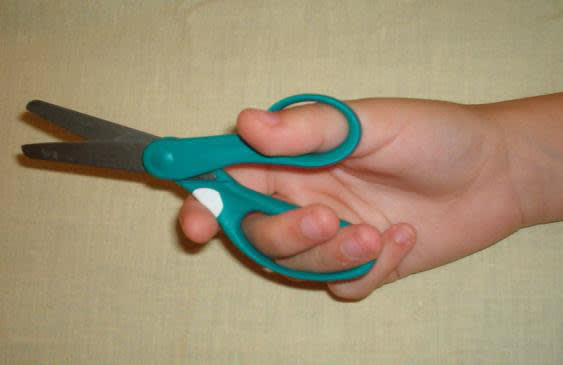 A hand holding teal scissors
