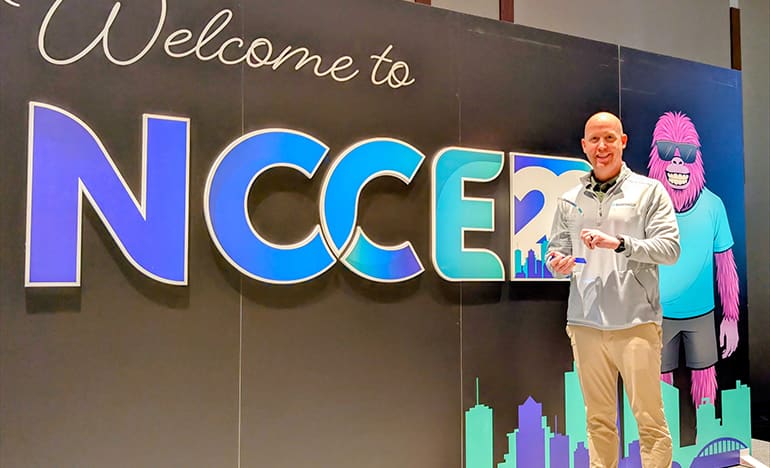 Forrest McKinnis stands in front of NCCE sign