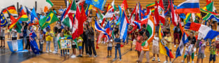 Students with flags from multiple countries gathered together holding the flags up