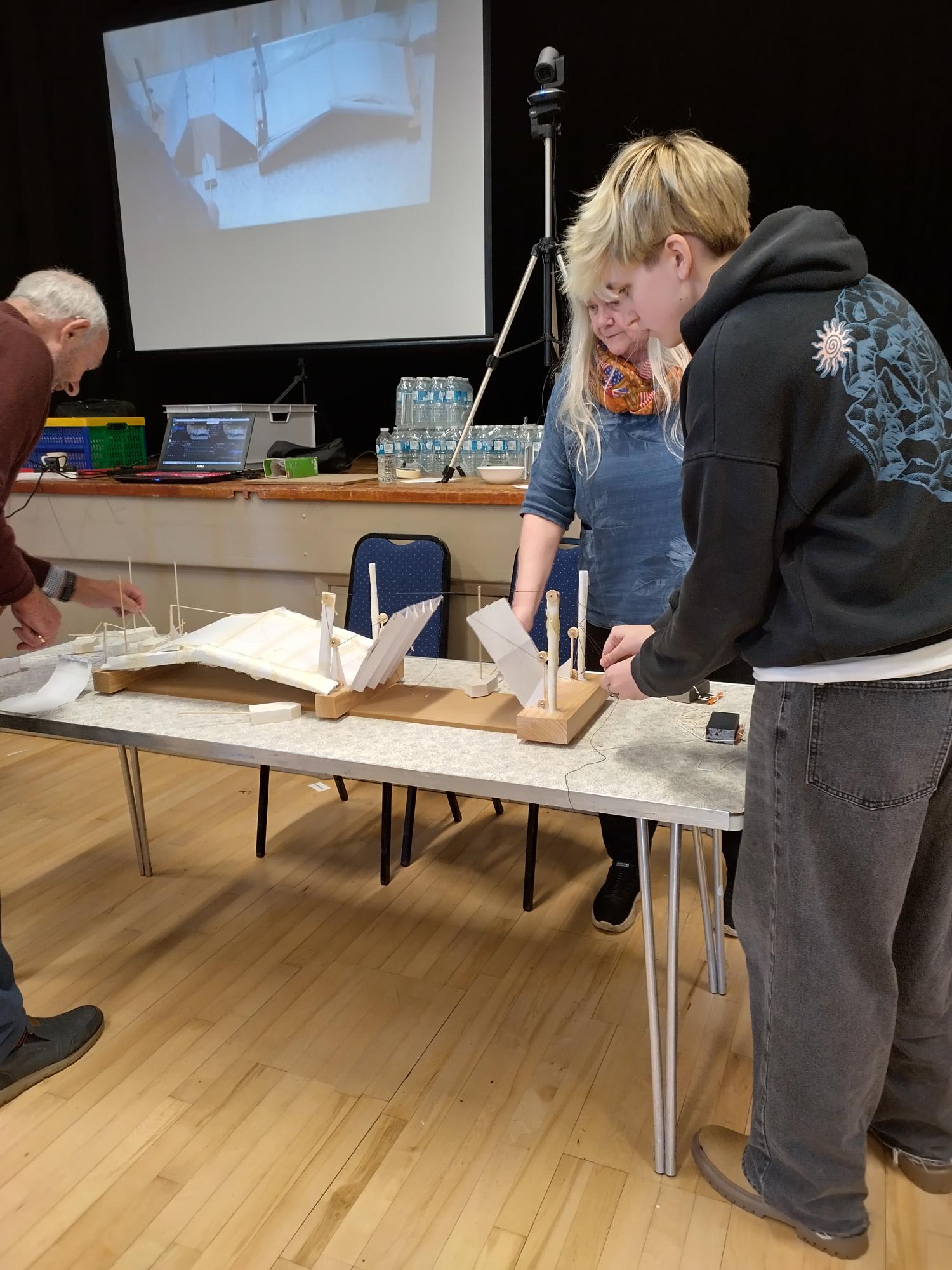 Students demonstrating and testing their bridge design in front of judges, highlighting hands-on STEM learning.