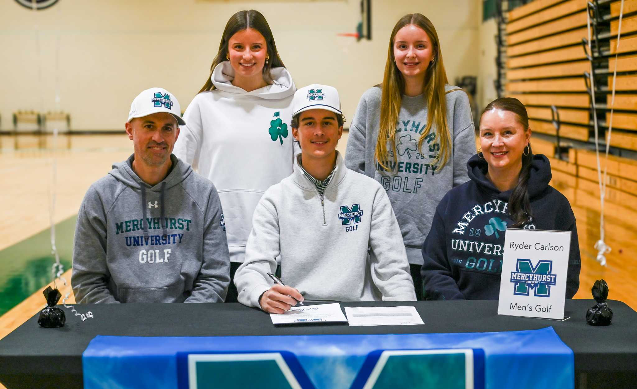 Holy Family senior Ryder Carlson signs to play college golf at Mercyhurst University with family and coaches behind him.
