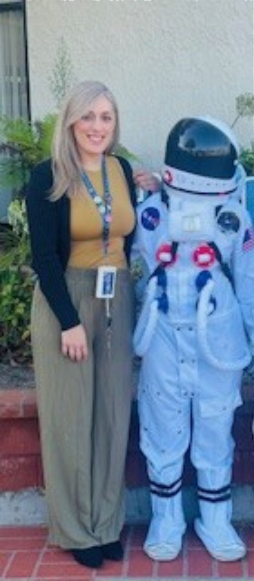 Diana Pelayo standing outdoors beside a student wearing a white astronaut costume and helmet.