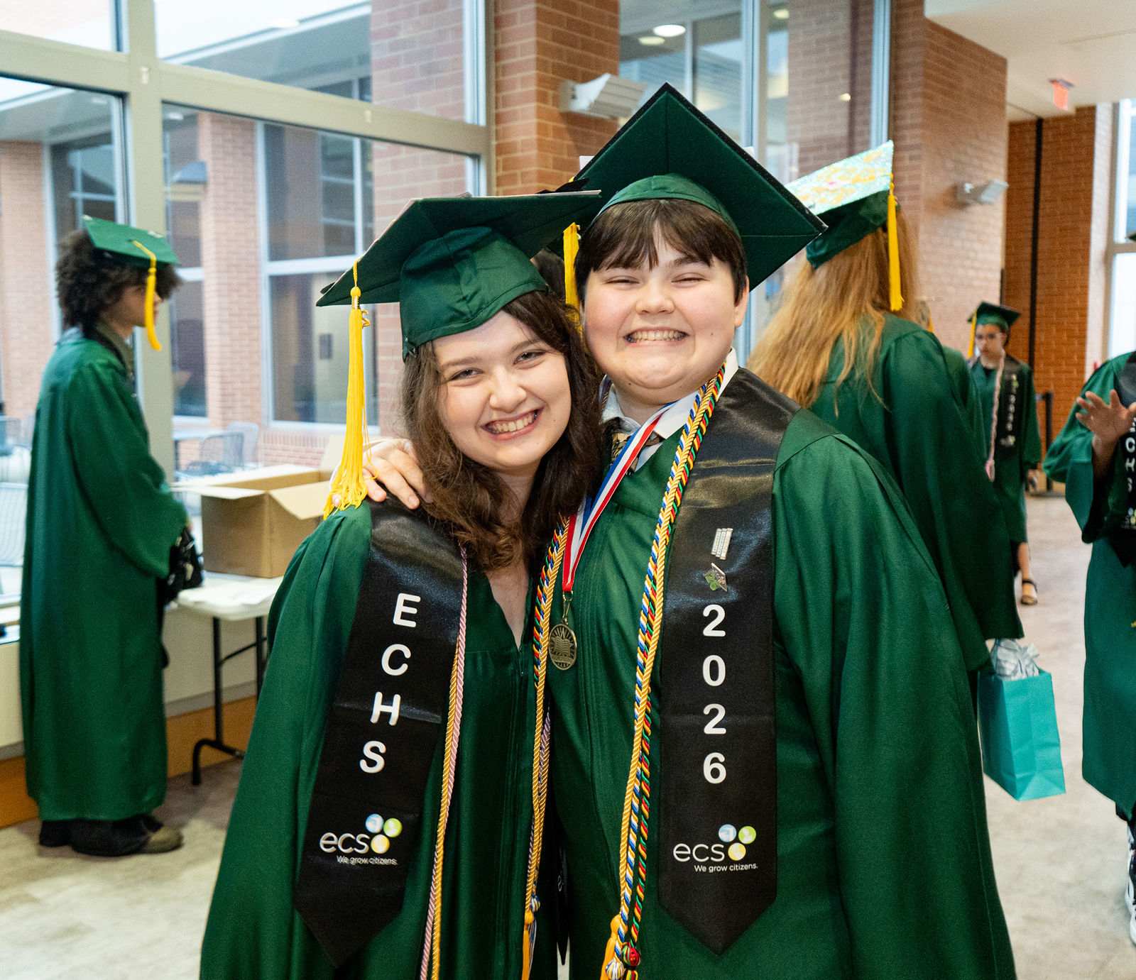 Two members of the ECHS Class of 2026 in caps and gowns