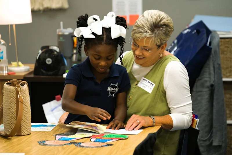 A BCA grandparent reading with her granddaughter at a Grands event on campus