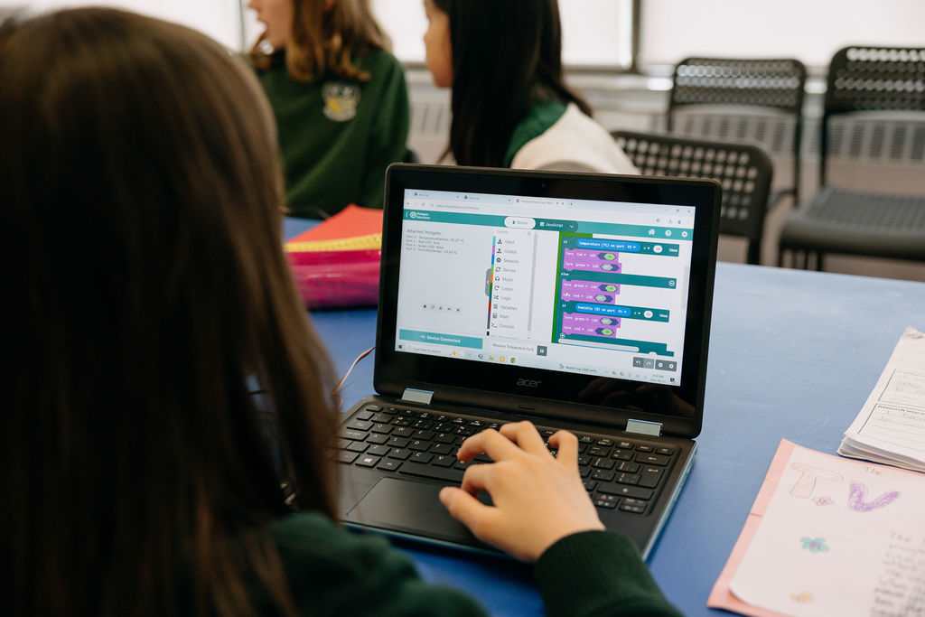 A Giles School student working through a coding exercise on a laptop