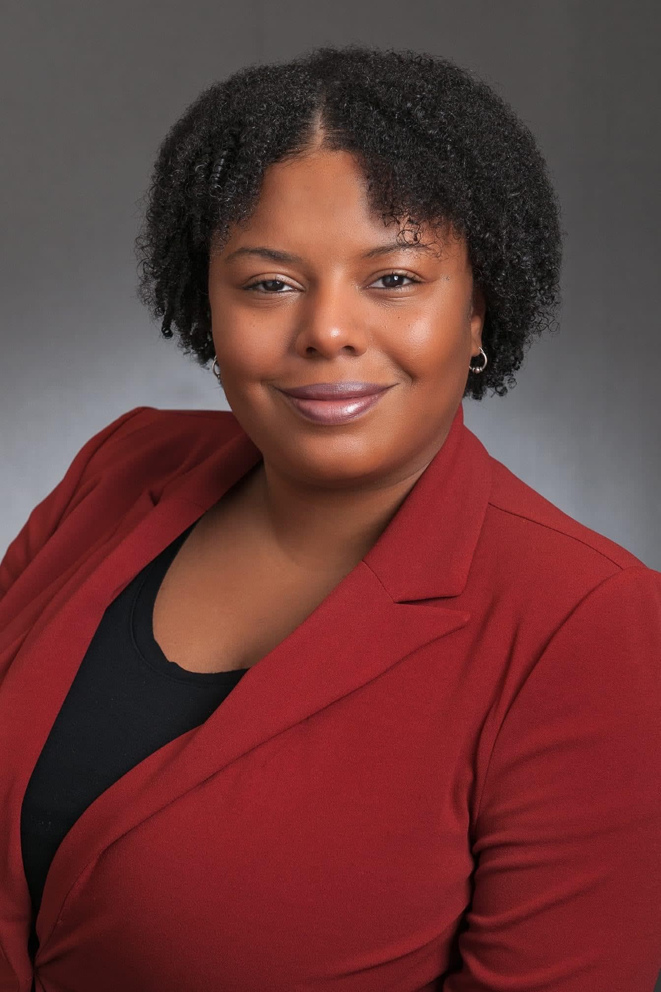 Chevelta Remo, valedictorian Class of 2007, wearing a red blazer in her professional headshot.