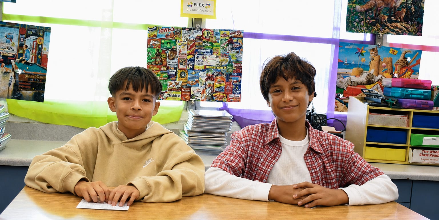 Two students sitting at desks in a decorated classroom.