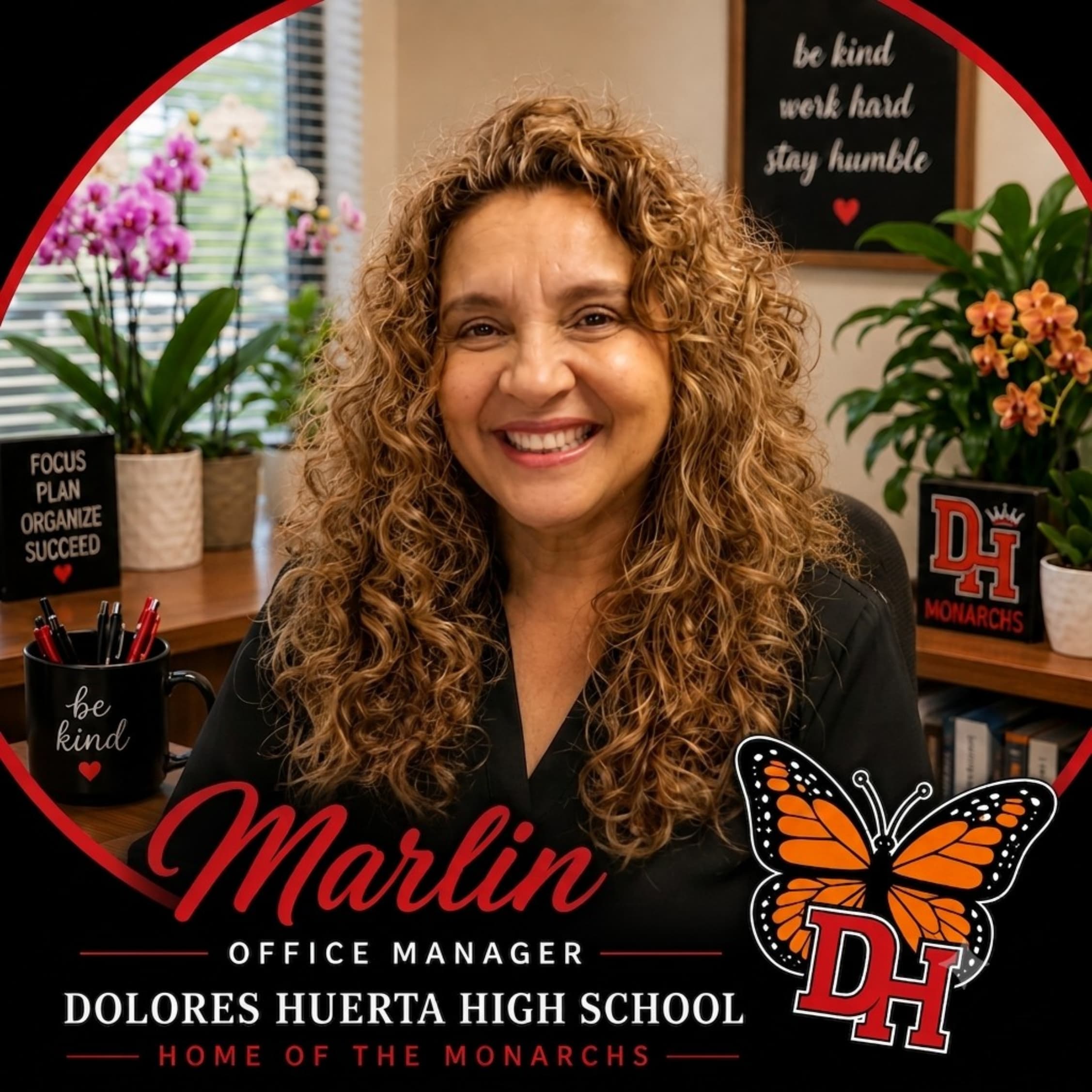 A smiling woman with curly hair sits at a desk with motivational signs and plants, while a monarch butterfly logo and school name are displayed in the background.