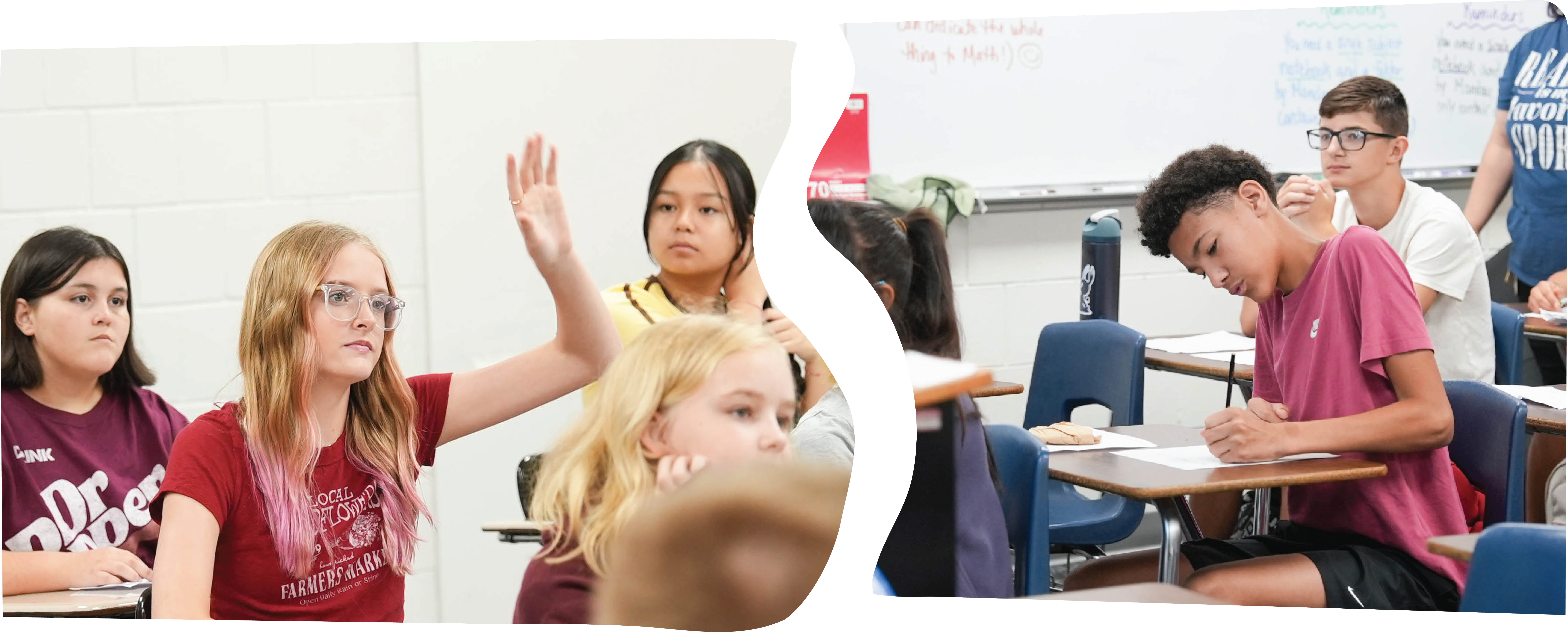 Students seated at desks in a classroom, one girl raising her hand