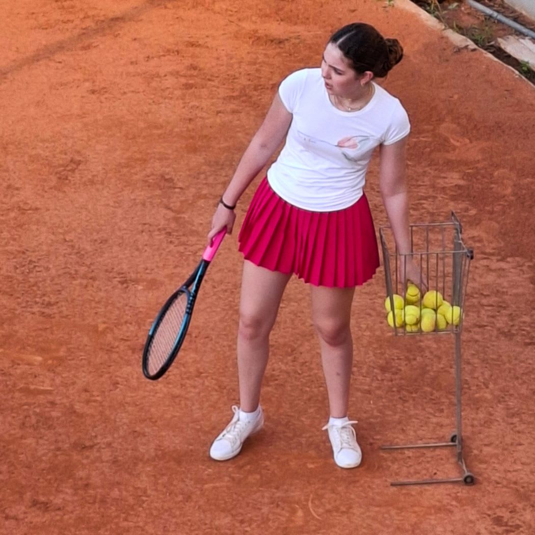 A CCI student practising tennis on a clay court