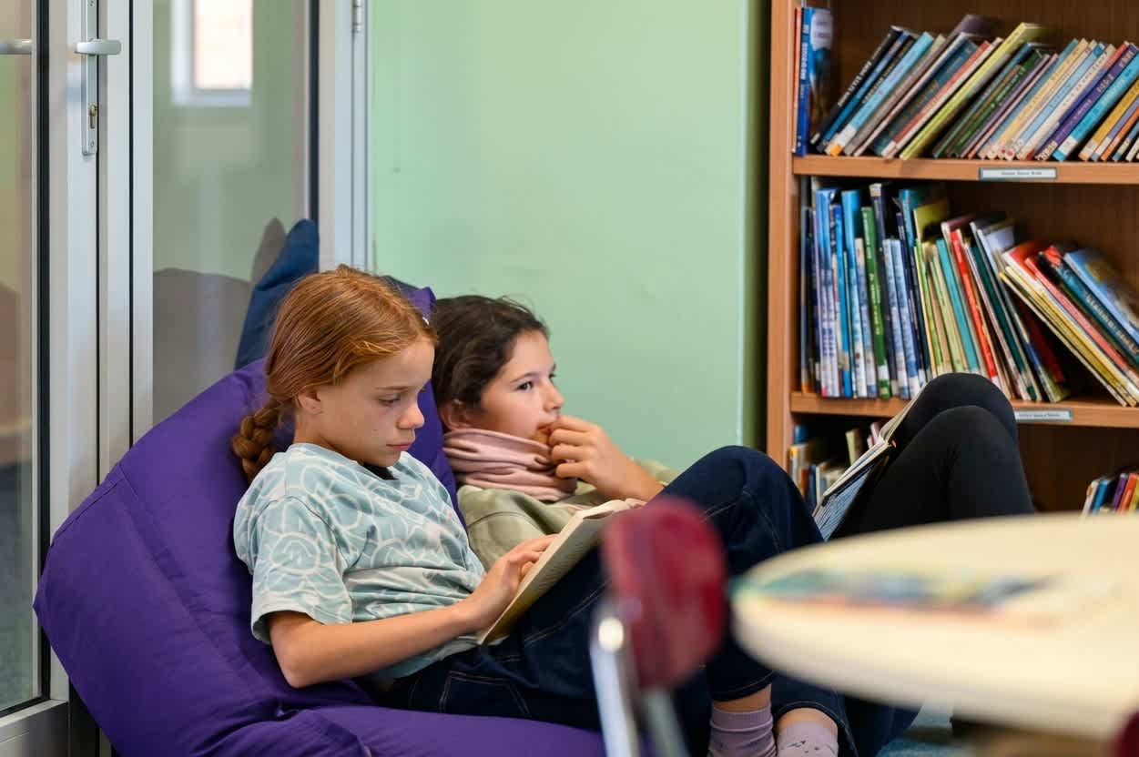 Two elementary students reading together on a beanbag in the library