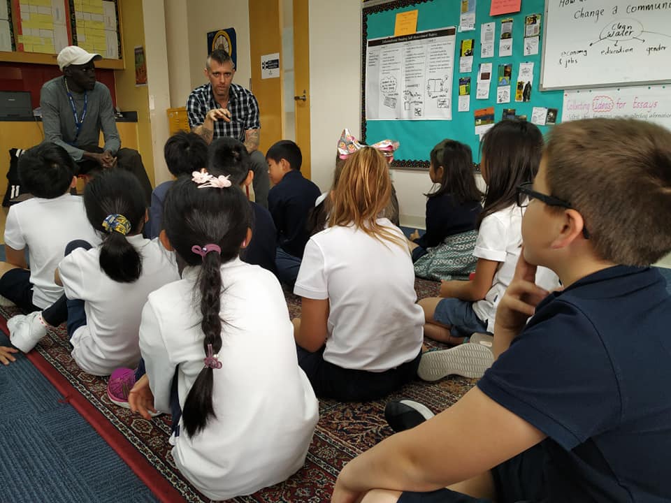 man with glasses telling a story to the children