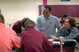 teacher smiles while working with group of students in science lab