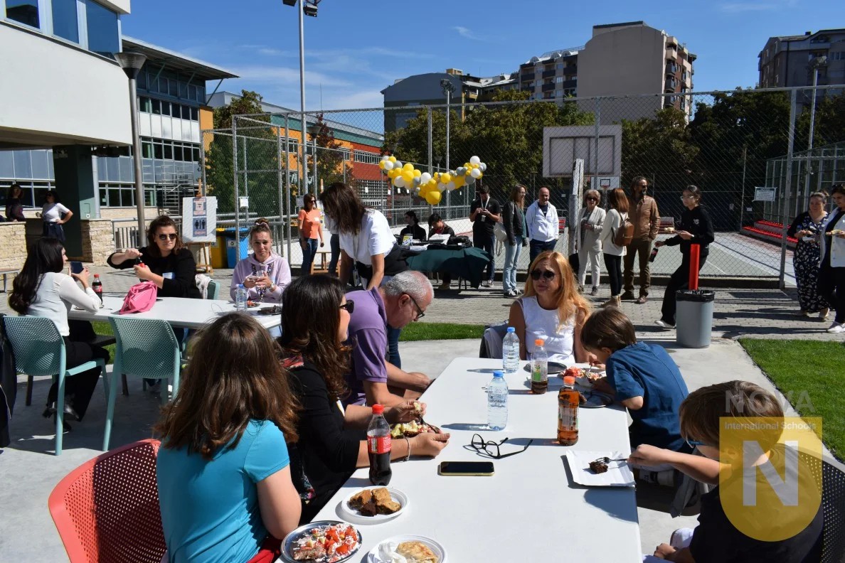Families sharing food at long tables in the schoolyard during the PTA barbecue